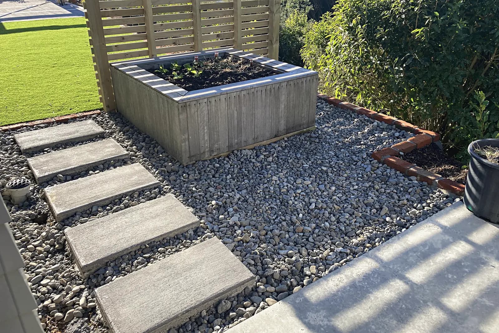 Stepping pavers through pebbles beside a raised planter, Aotea