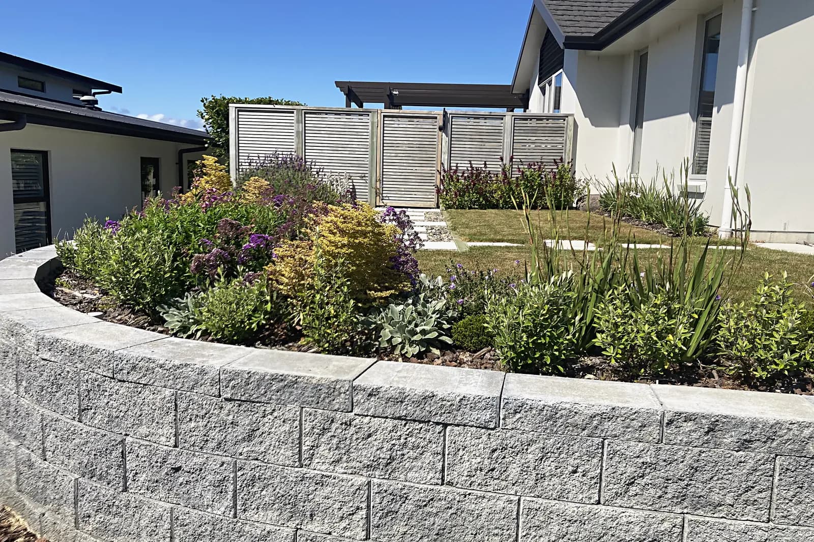Block retaining wall and garden bed beside a house, Aotea