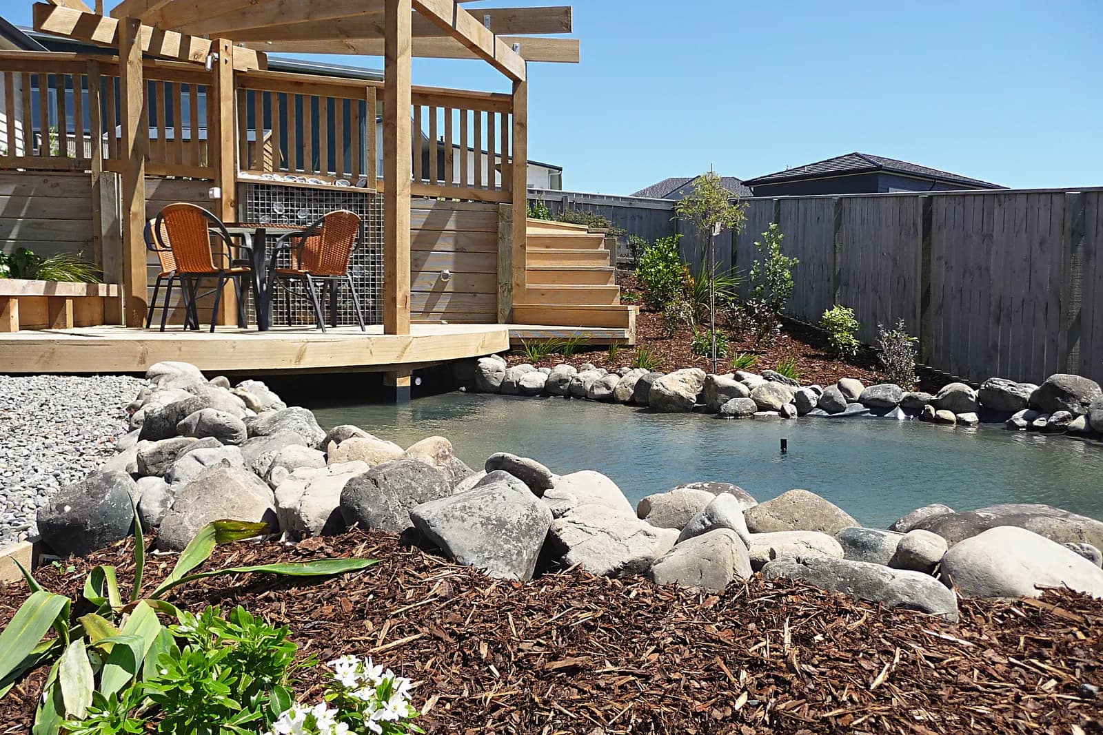 Boulder-edged pond beside a timber deck, Aotea