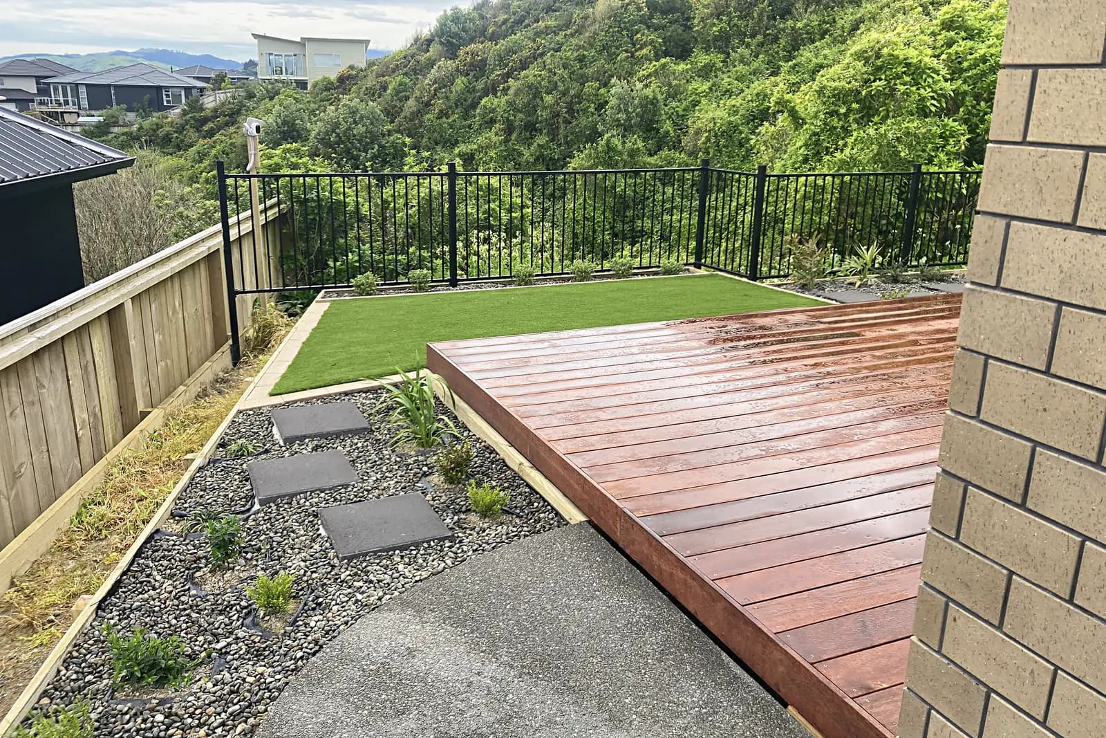 Hardwood deck beside artificial turf and a pebble bed with stepping stones, Aotea