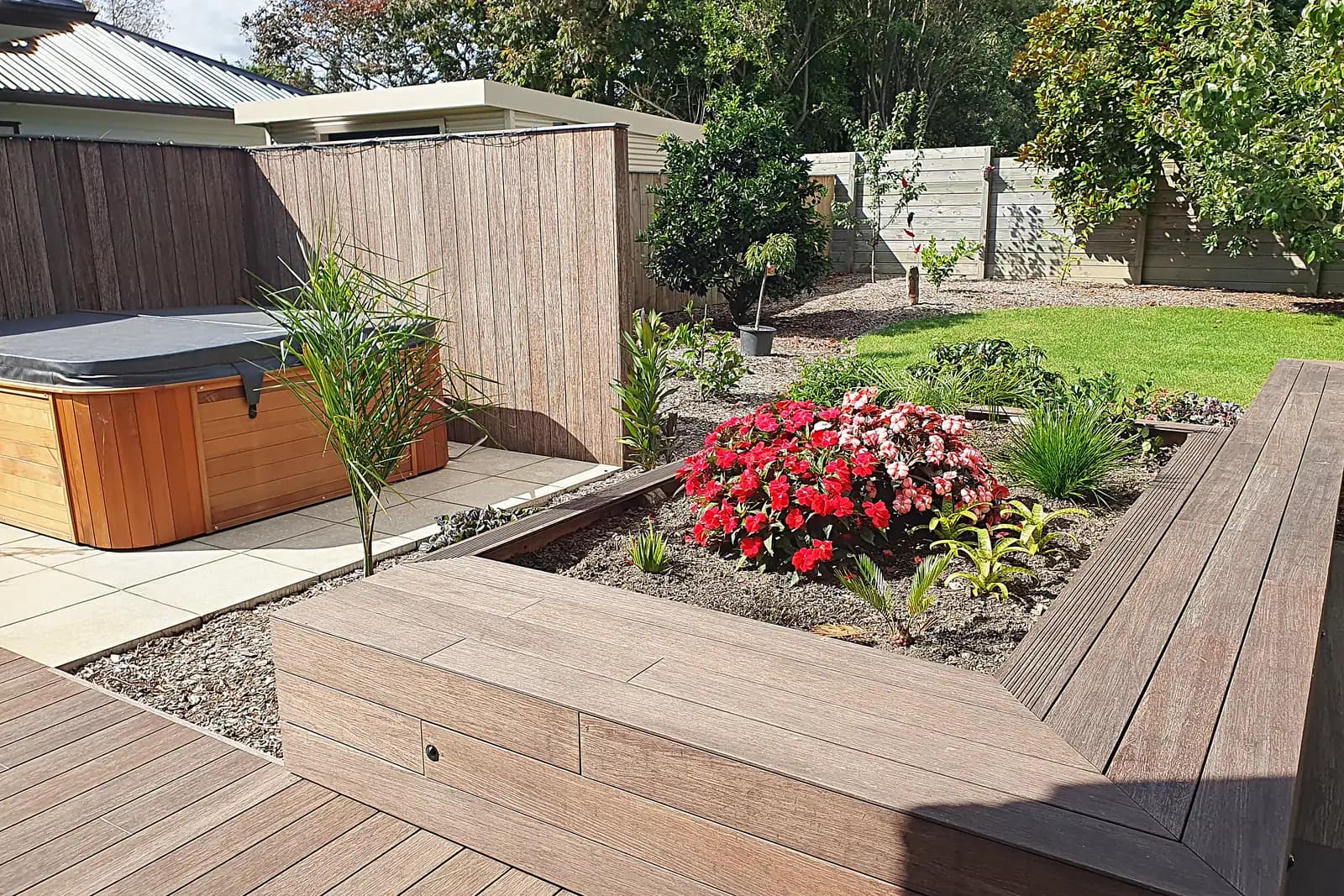 Timber bench seat around a planted bed next to a spa, Otaki