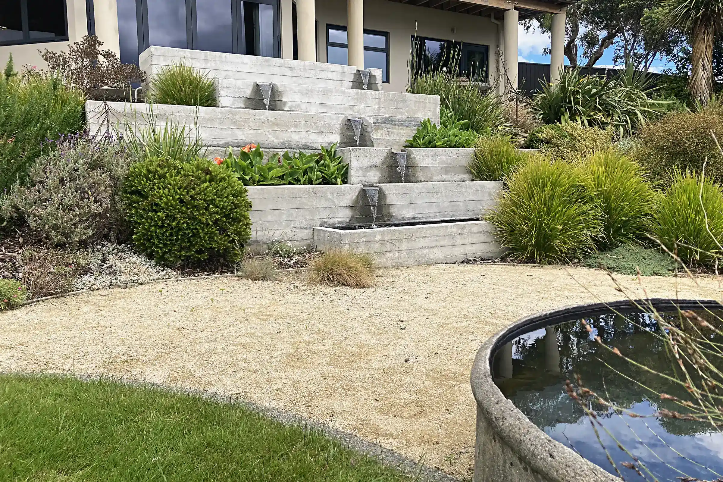 Terraced concrete planters and a round pond in a coastal garden, Paremata