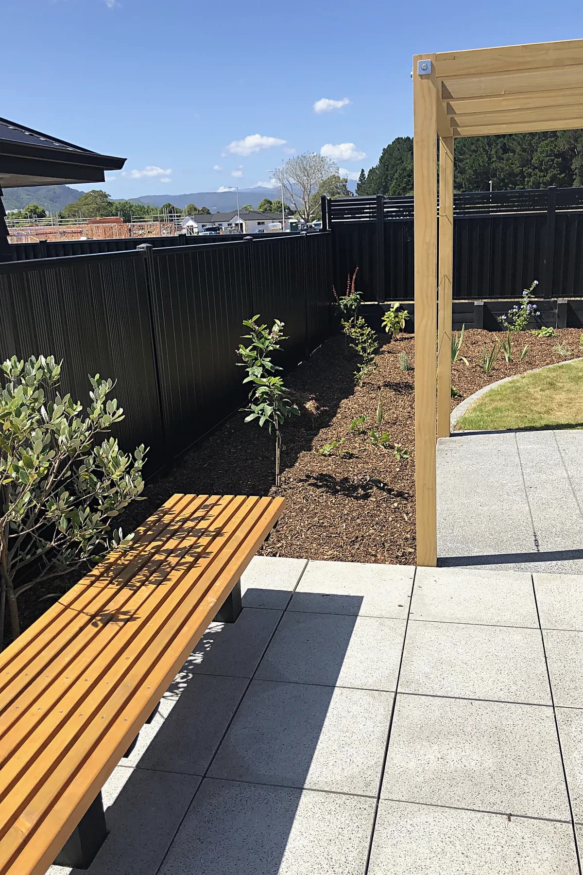 Timber bench on paving beside a pergola, Trentham