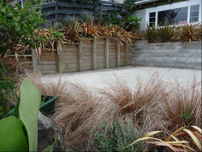 A distinctivelandscapes sloping wood/concreate retaining wall made of The wall is supporting a slope of soil